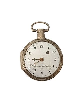 a silver pocket watch that is on display on a white background