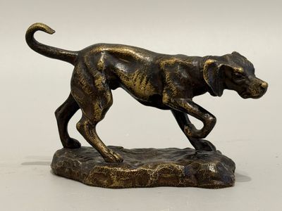 bronze statue of a dog running on a rock on a white background
