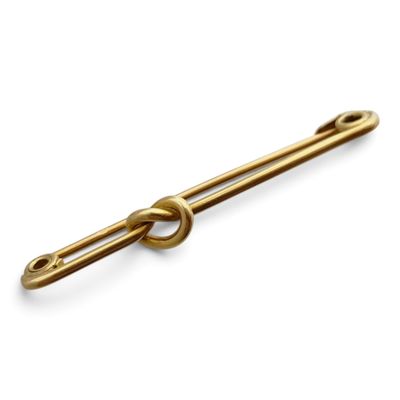 une broche en or ornée d'un nœud, sur fond blanc