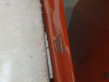 a close up of a piece of orange paint on the side of a car