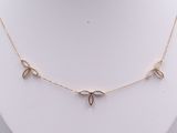 a gold necklace with three leaves on a white mannequin