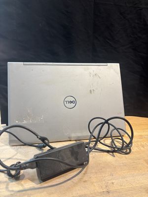 un ordinateur portable Dell posé sur une table en bois, avec son chargeur branché