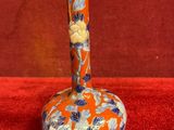 an orange and blue vase sitting on top of a red surface