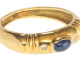 gros plan d'une bague en or avec une pierre bleue et des diamants