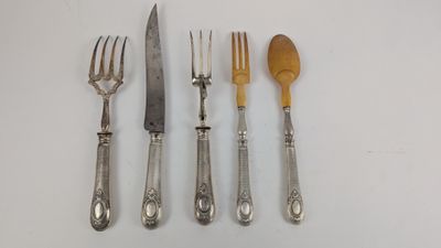 quatre fourchettes, un couteau, une cuillère et un repose-cuillère posés sur une surface blanche