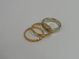 three gold rings on a white surface