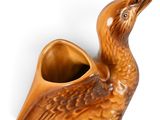 a brown vase with a bird on it on a white surface