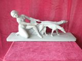 statue représentant une femme et un chien posée sur une table recouverte d'une nappe rose