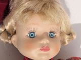 a doll with blonde hair and blue eyes wearing a red hat