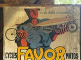 une affiche sur laquelle on peut lire « Cycles Favor Moto » accrochée au mur