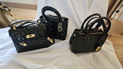 trois sacs à main noirs posés sur un drap blanc, avec une poignée dorée