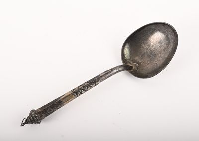 une cuillère en argent avec un manche sur une surface blanche