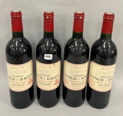 quatre bouteilles de vin sont alignées sur une surface blanche