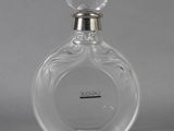 a clear glass bottle with a silver top sitting on a gray surface