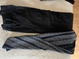 two pairs of black pants and a scarf laying on top of a bed