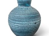 un vase bleu posé sur une surface blanche