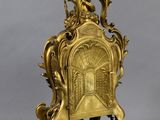an image of a gold clock on a stand on a gray background