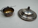 silver plate with a lid and a spoon on a white surface