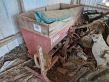 un chariot rouge posé au milieu d'un tas de vieilleries