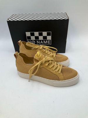 a pair of tan sneakers with white soles and a black box