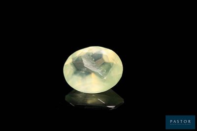 une pierre de jade jaune posée sur une surface noire, avec un fond noir
