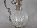 a silver and glass pitcher with a handle on a table
