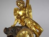 a gold statue of an angel sitting on top of a clock