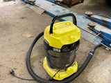 a yellow vacuum sitting on the ground next to a blue car
