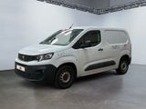 La camionnette blanche est garée dans une grande pièce aux murs blancs.