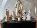 une statue représentant une femme, entourée de figurines, sous un dôme de verre