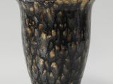 a black and gold vase sitting on top of a white table