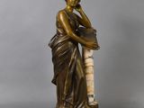 an antique bronze statue of a woman holding a vase