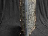 an old book sitting on top of a black cloth covered table