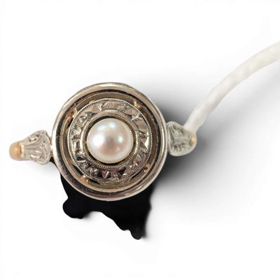 a white pearl in the middle of a silver and gold ring