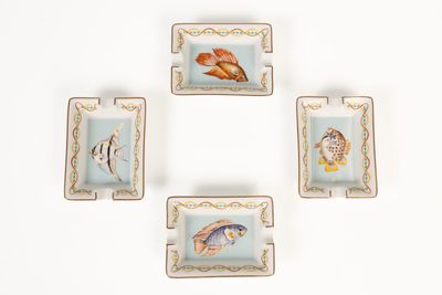 quatre assiettes carrées ornées de poissons et de coquillages, posées sur un fond blanc