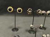 several pairs of earrings are displayed on a stand on a table