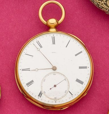 a gold pocket watch with roman numerals on a pink surface