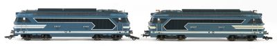 two blue trains sitting side by side on a white surface