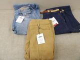 trois paires de pantalons pour homme posées les unes à côté des autres sur un canapé