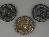 trois pièces de monnaie romaines anciennes posées sur une surface blanche