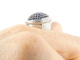 a person holding a ring with blue stones on it