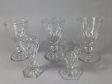 quatre verres à pied en verre transparent posés sur une table blanche