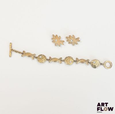 une photo représentant un bracelet en or et deux breloques sur un fond blanc