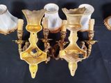three gold and white glass wall sconces on a black background