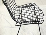 a black wire chair that is on a white sheet