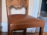 a wooden chair with a brown leather seat in a room