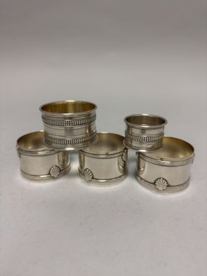 quatre serviettes et tasses argentées posées sur une surface blanche