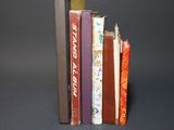 several books are stacked on top of each other on a black surface