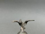 an old silver bell with a bird on top of it