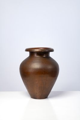 un petit vase marron posé sur une table blanche